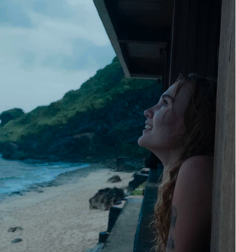 Iana Kallina looking out from a balcony over a beach in Bali