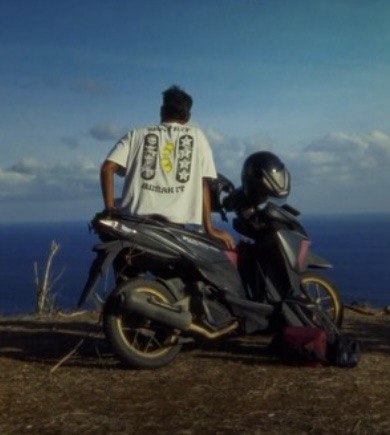 Person leaning on a parked scooter on a cliff edge, ocean behind