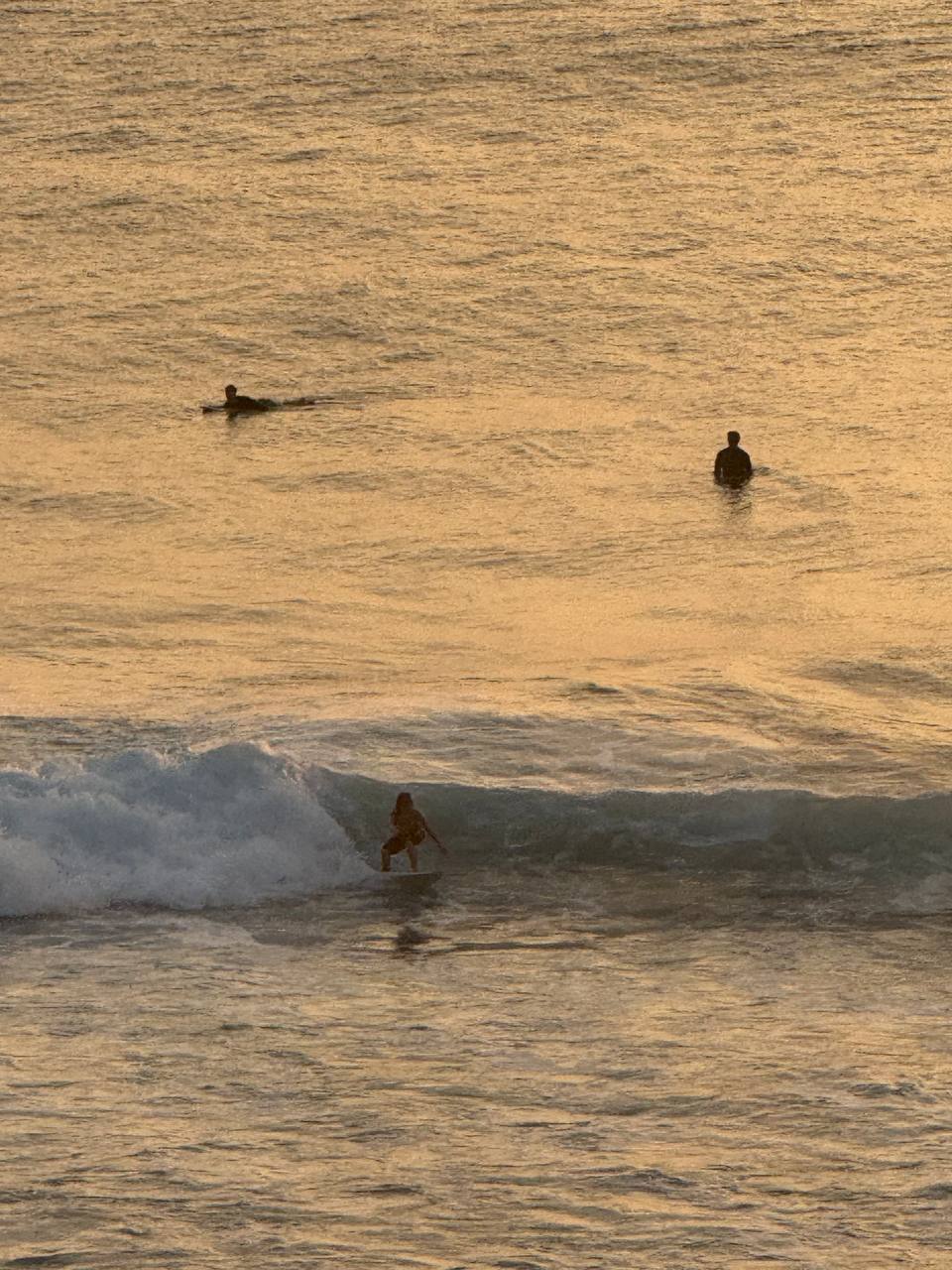Surfers riding golden-hour waves at Uluwatu