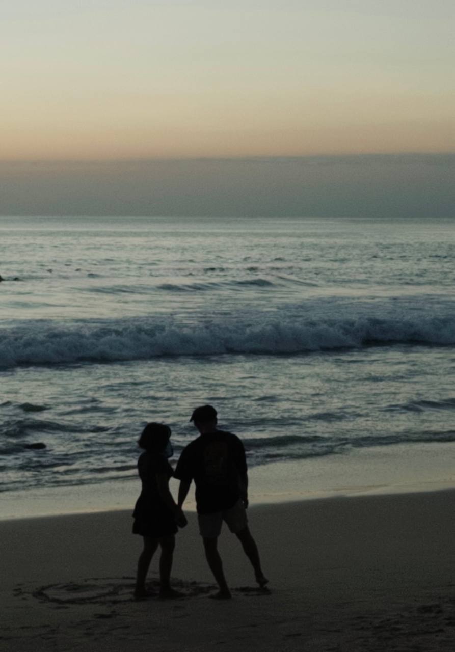 A couple silhouetted on the beach at dusk, Uluwatu